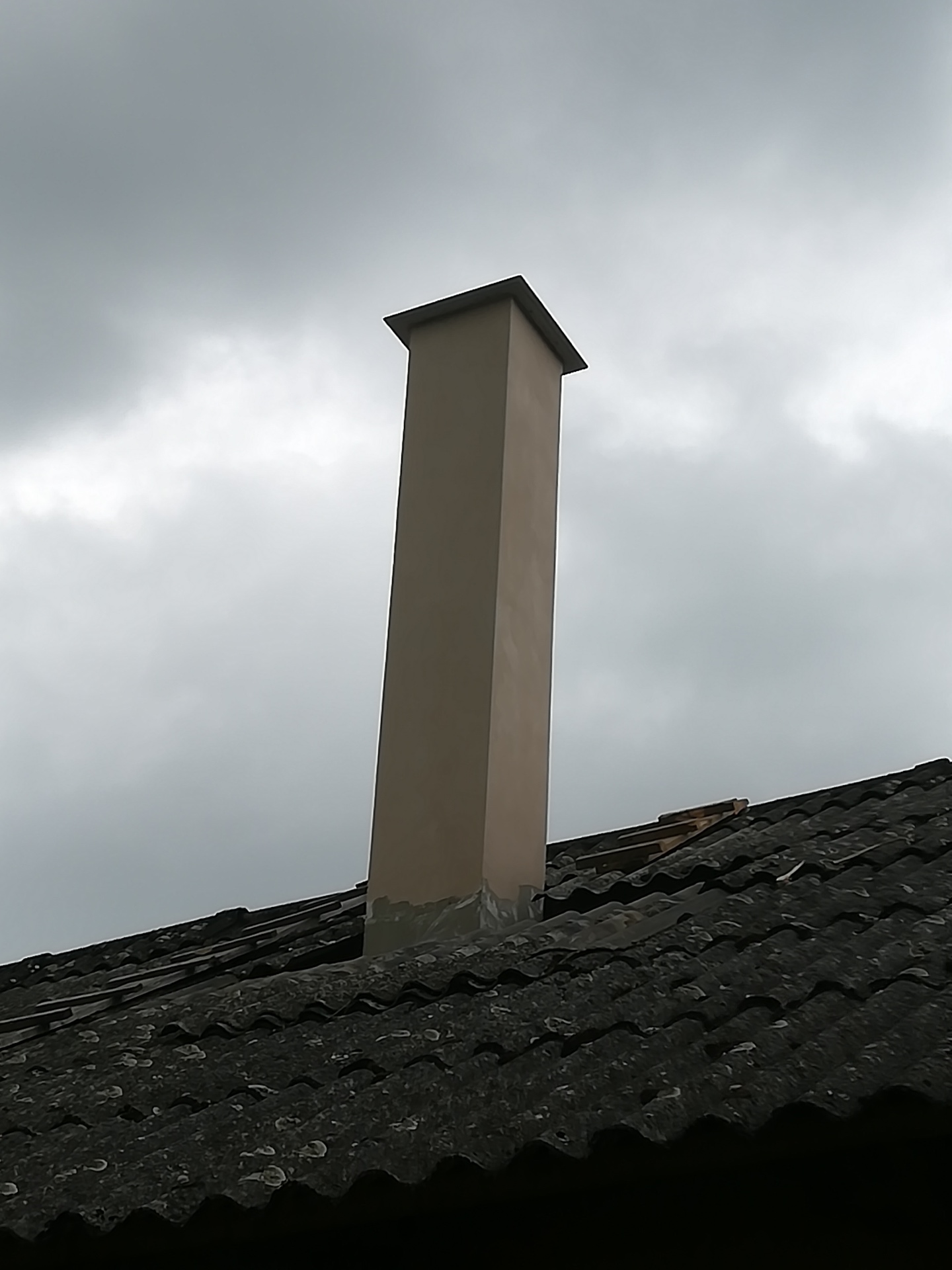 Nově omítnutý komín na eternitové střeše